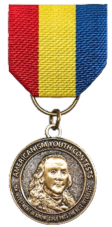 Americanism Youth Contests medal consisting of a ribbon of red, yellow and blue cloth suspending a bronze medal with an image of Benjamin Franklin encircled with his quoted words, An Investment of Knowledge Pays the Best Interest